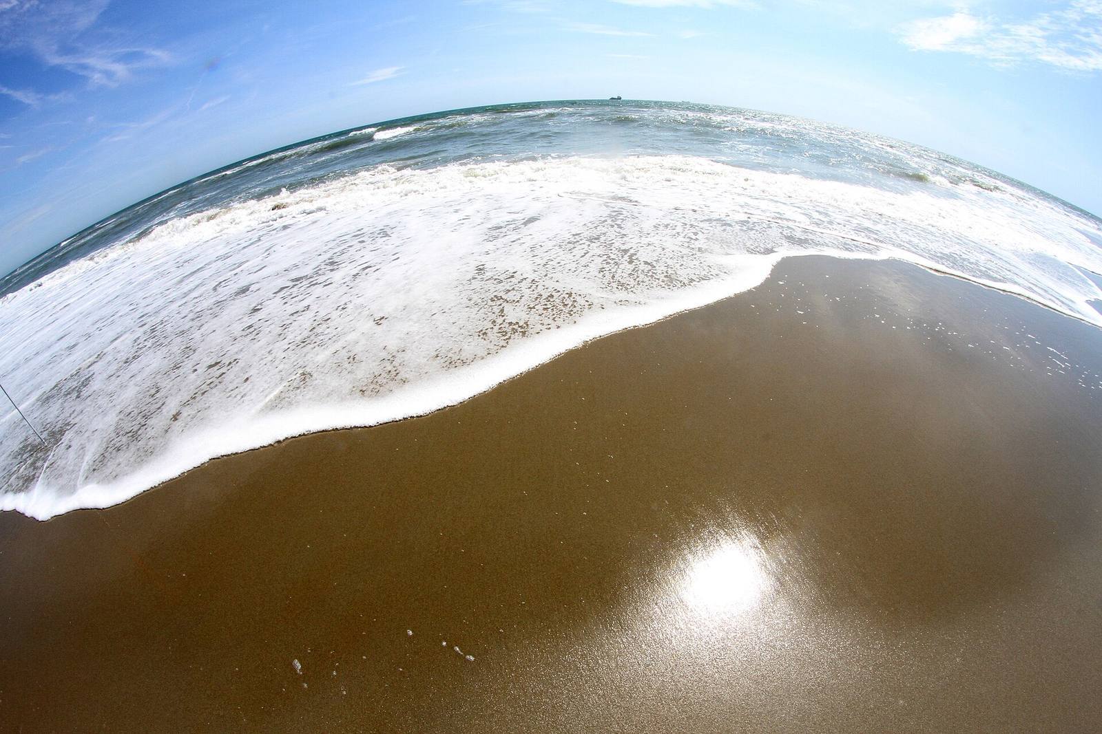 Schaumkante einer Welle, die über nassen Sand gleitet