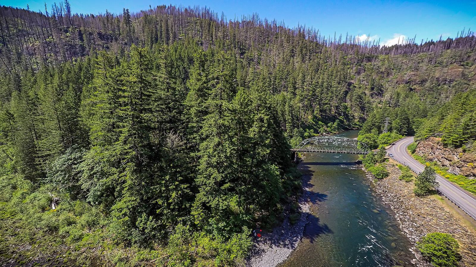 Aerial view of a forested river valley with a bridge