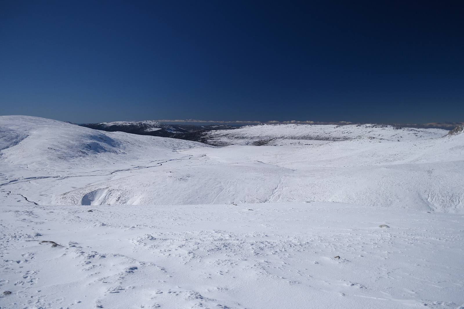 Snow-covered mountain plateau under a deep blue sky